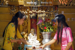 Junge Burmesinnen waschen den Buddha, der dem Wochentag ihres Geburtstages zugeordnet ist. Sule Pagode. Yangon. Rangun. Myanmar